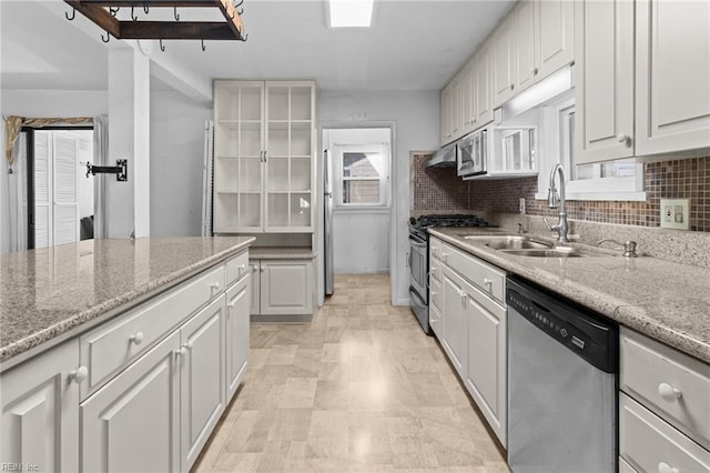 kitchen featuring stainless steel appliances, white cabinets, sink, and light stone countertops