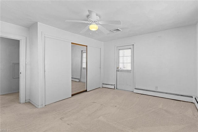 unfurnished bedroom with light carpet, a baseboard heating unit, and ceiling fan