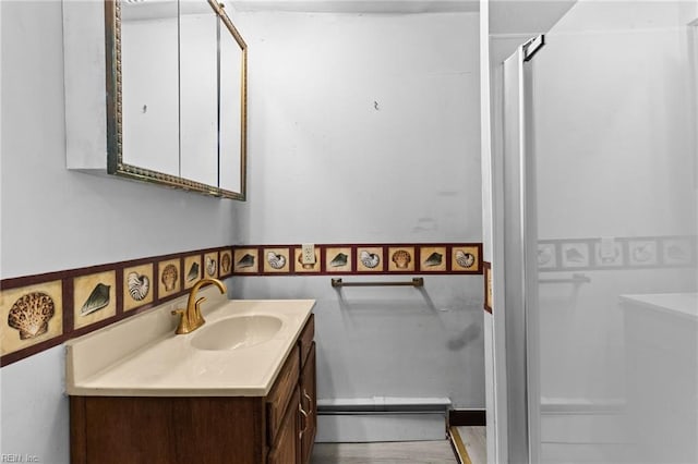 bathroom with tile walls, vanity, and a baseboard heating unit