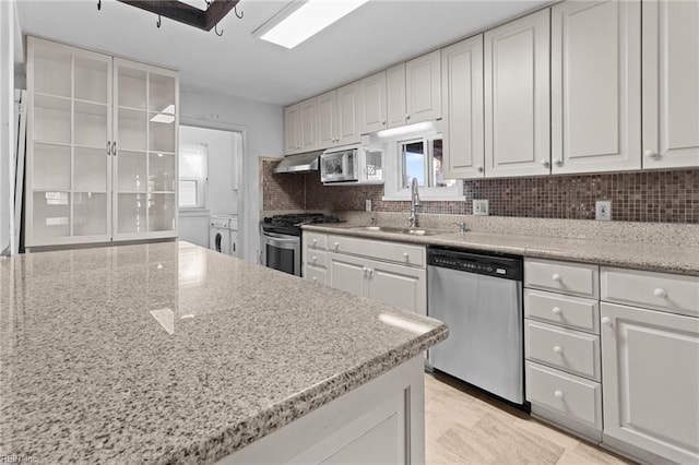 kitchen with light stone counters, white cabinets, appliances with stainless steel finishes, and backsplash