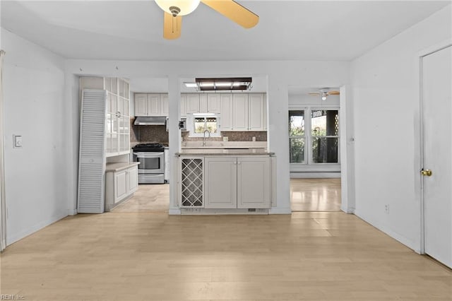 kitchen with gas stove, sink, backsplash, and light wood-type flooring