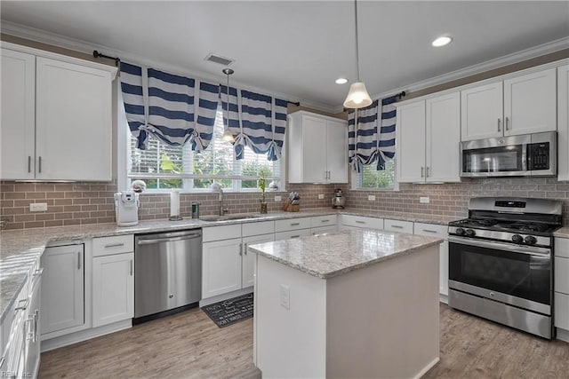 kitchen featuring stainless steel appliances, a center island, pendant lighting, sink, and white cabinetry