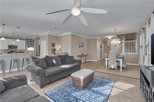 living room with light hardwood / wood-style flooring, crown molding, and ceiling fan with notable chandelier