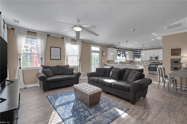 living room with ornamental molding, ceiling fan, and light hardwood / wood-style flooring