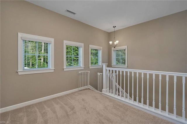 unfurnished room featuring light colored carpet and a chandelier