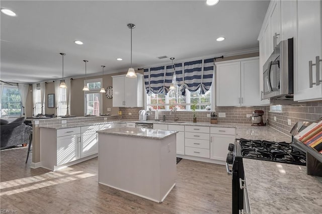 kitchen with decorative light fixtures, kitchen peninsula, appliances with stainless steel finishes, and a center island