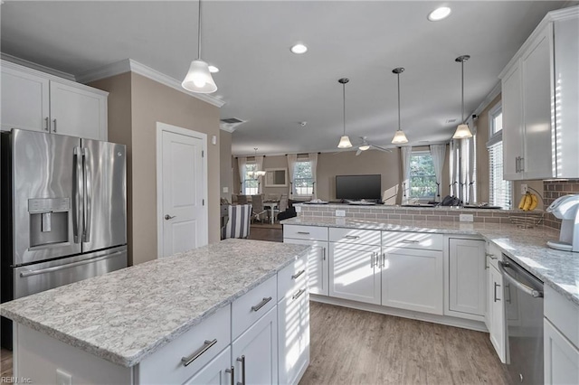 kitchen with a center island, ornamental molding, white cabinets, appliances with stainless steel finishes, and ceiling fan