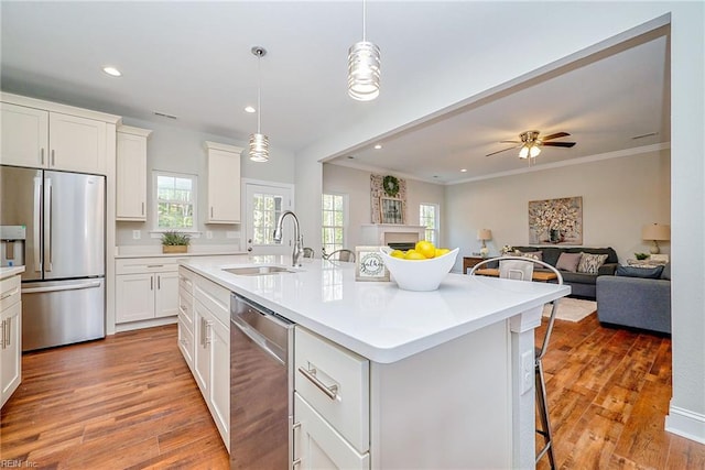 kitchen with a breakfast bar area, stainless steel appliances, open floor plan, a sink, and light wood-type flooring