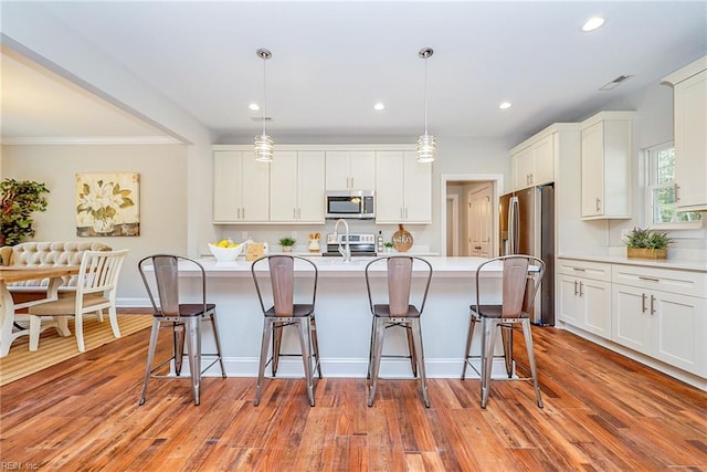 kitchen with appliances with stainless steel finishes, a center island with sink, a sink, and a breakfast bar area