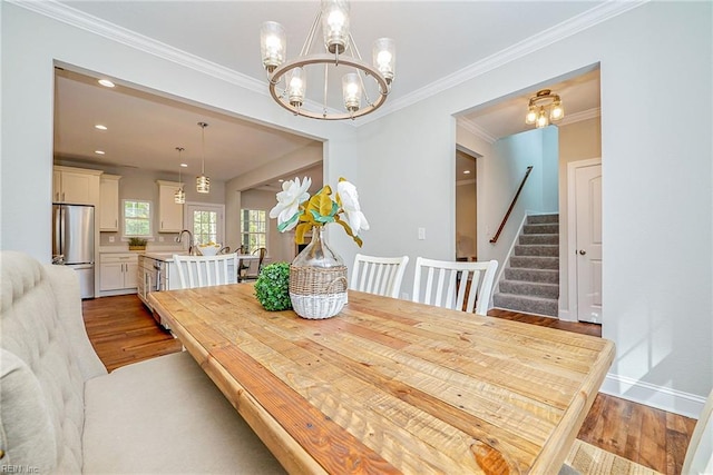 dining area featuring crown molding, stairway, wood finished floors, and a notable chandelier