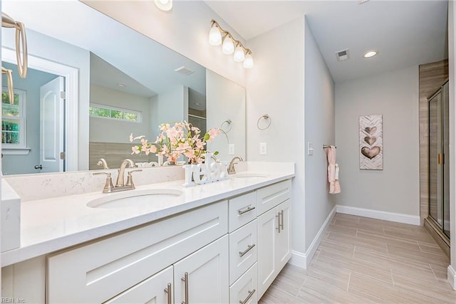 full bath with double vanity, a sink, visible vents, and a shower with door