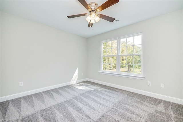 carpeted empty room featuring ceiling fan, visible vents, and baseboards