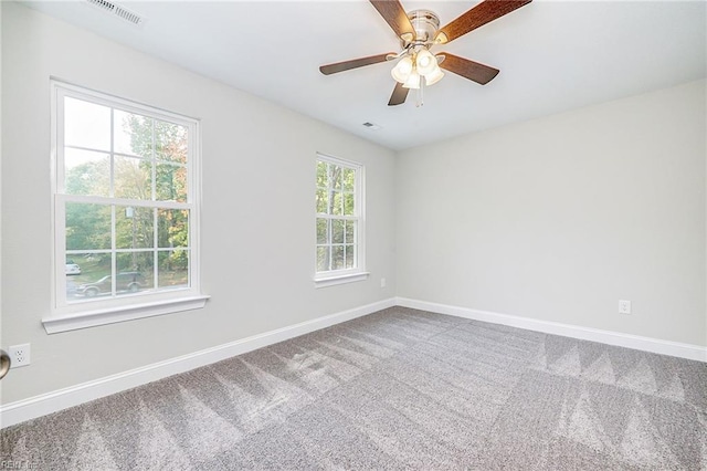 carpeted empty room featuring a ceiling fan, visible vents, and baseboards