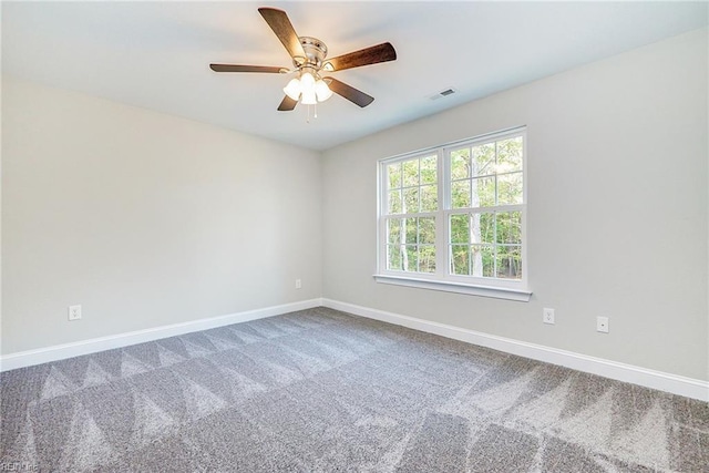 carpeted empty room featuring a ceiling fan, visible vents, and baseboards