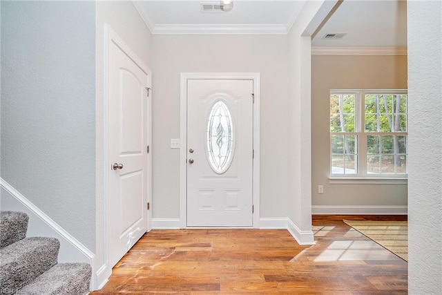 foyer with ornamental molding, visible vents, stairway, and wood finished floors