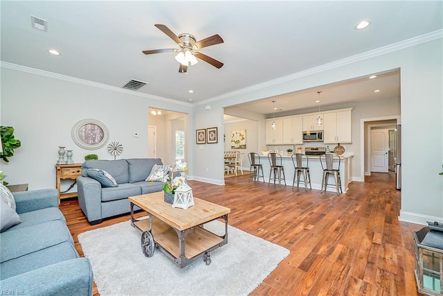 living area with recessed lighting, light wood-type flooring, visible vents, and baseboards