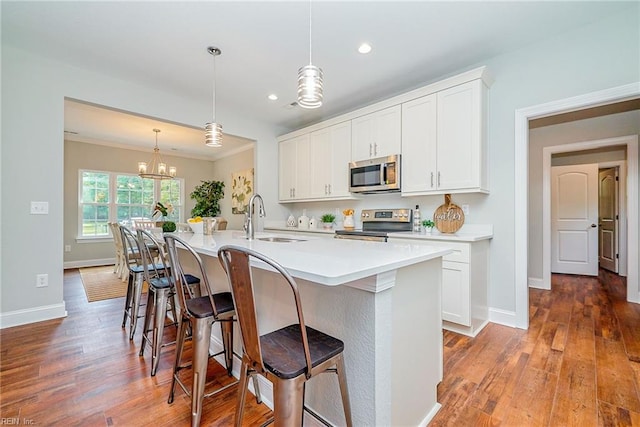 kitchen featuring stainless steel appliances, a kitchen island with sink, a sink, and light wood finished floors