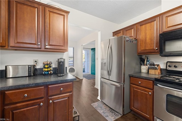 kitchen with a textured ceiling, appliances with stainless steel finishes, and dark hardwood / wood-style floors