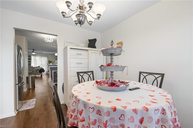 dining area with ceiling fan with notable chandelier and dark wood-type flooring