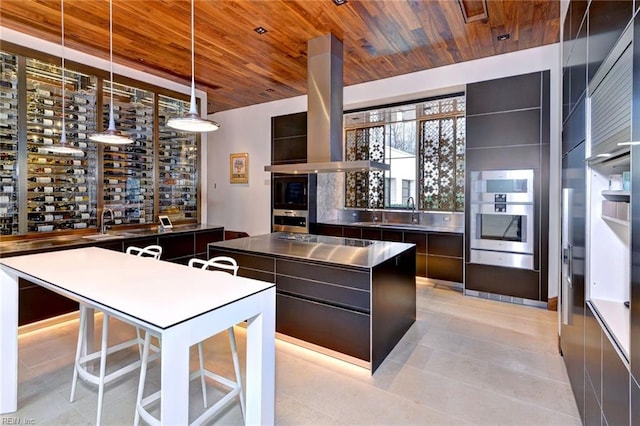 kitchen with decorative light fixtures, island exhaust hood, a kitchen island, double oven, and wooden ceiling