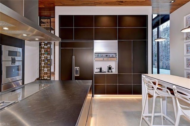 kitchen with paneled built in fridge, light tile patterned flooring, tile walls, stainless steel double oven, and range hood