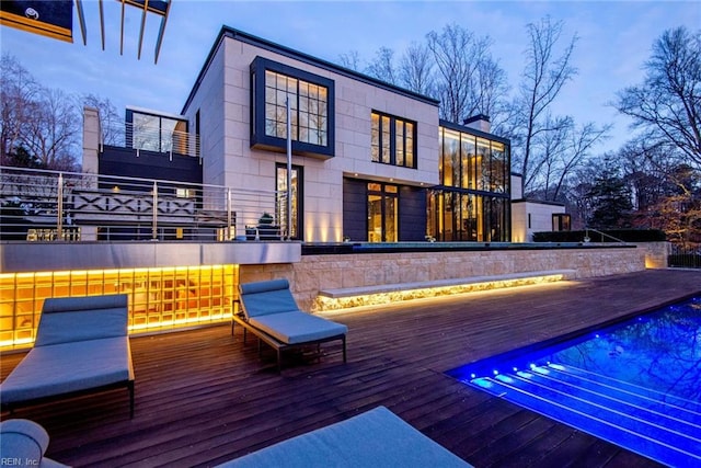 deck at dusk with a swimming pool