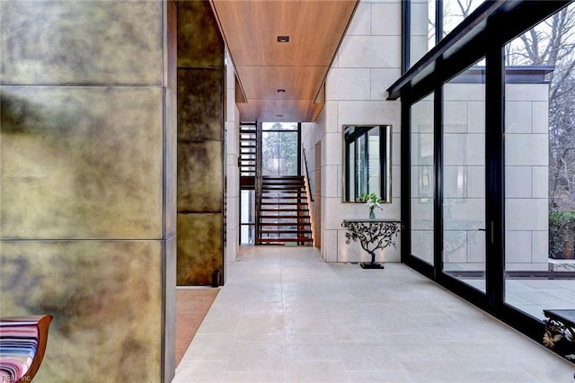 hall featuring a high ceiling, wood ceiling, and expansive windows