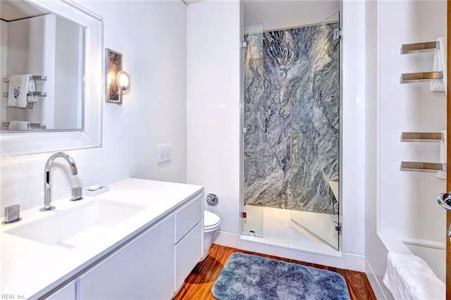 bathroom with toilet, hardwood / wood-style flooring, a shower with shower door, and vanity