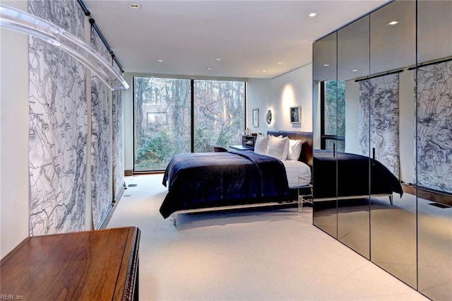 bedroom with floor to ceiling windows and light carpet