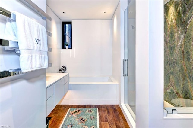 bathroom with wood-type flooring, vanity, and independent shower and bath