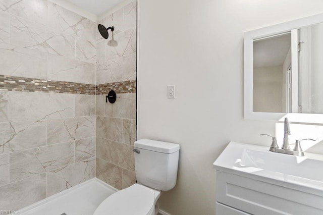 bathroom featuring toilet, tiled shower, and vanity