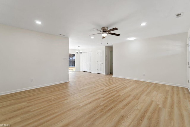 unfurnished living room featuring ceiling fan with notable chandelier and light hardwood / wood-style floors