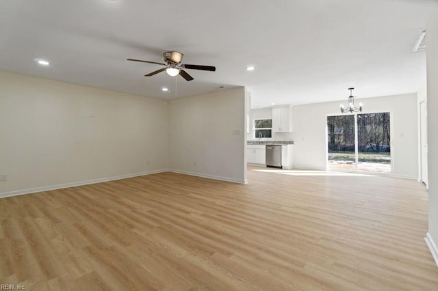 unfurnished living room featuring ceiling fan with notable chandelier, sink, light wood-type flooring, and a healthy amount of sunlight