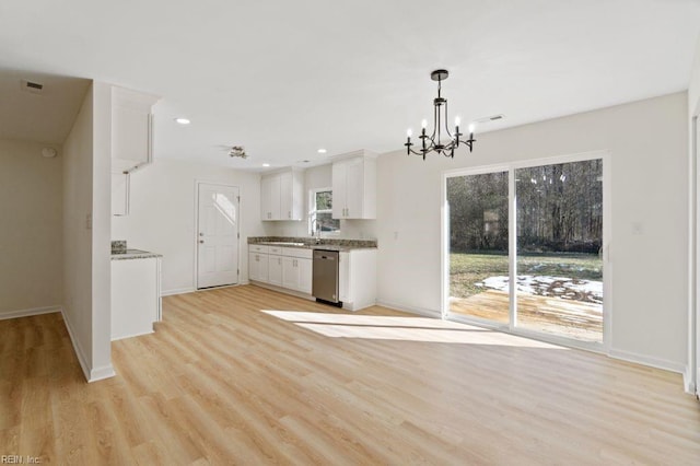 kitchen featuring stainless steel dishwasher, hanging light fixtures, a notable chandelier, light wood-type flooring, and white cabinetry