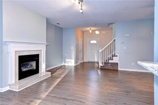 unfurnished living room featuring dark wood-type flooring, a high end fireplace, and a textured ceiling