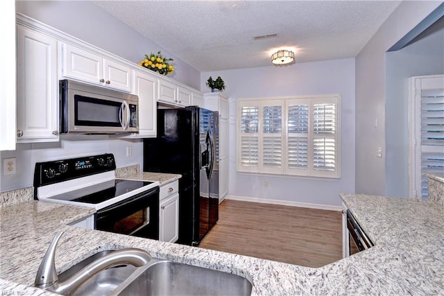 kitchen featuring a textured ceiling, light stone countertops, white cabinetry, and black appliances