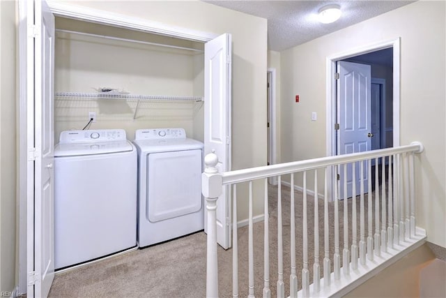 laundry area with a textured ceiling, separate washer and dryer, and light carpet