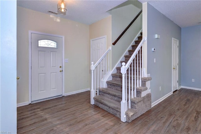 entryway featuring dark wood-type flooring and a textured ceiling