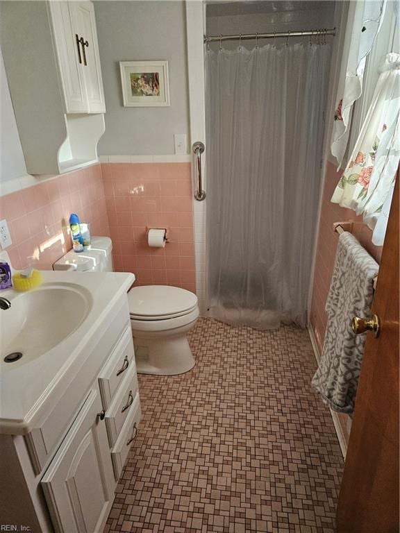 bathroom with tile walls, a shower with curtain, vanity, and toilet