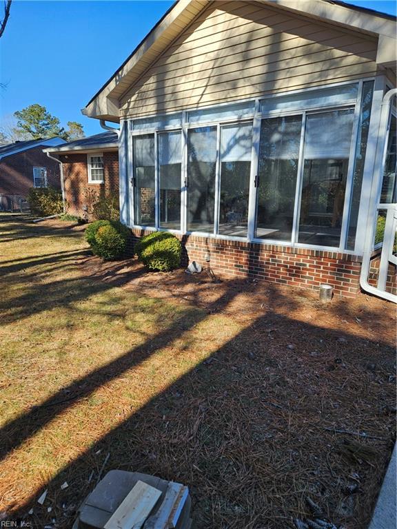 rear view of house featuring a yard and a sunroom