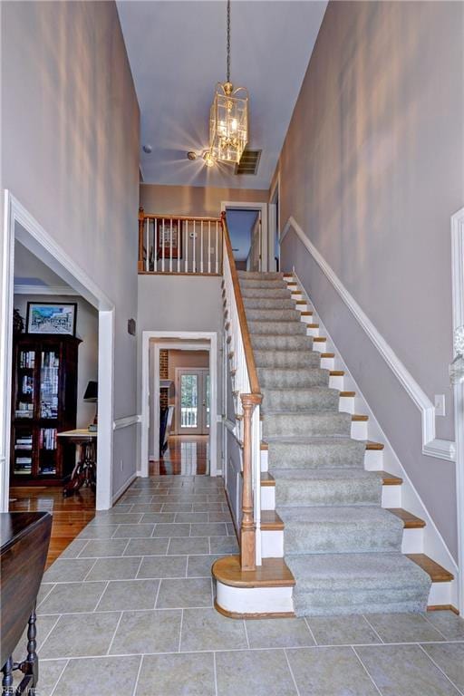 stairway featuring a towering ceiling and a chandelier