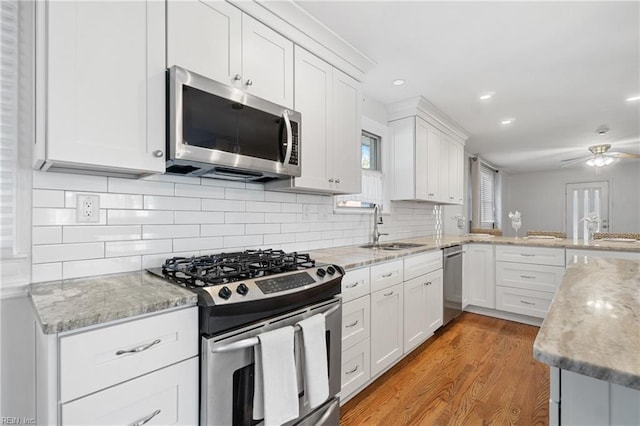 kitchen with white cabinetry, ceiling fan, appliances with stainless steel finishes, light hardwood / wood-style flooring, and sink