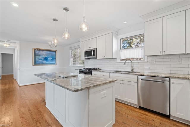 kitchen with appliances with stainless steel finishes, sink, white cabinetry, and a center island