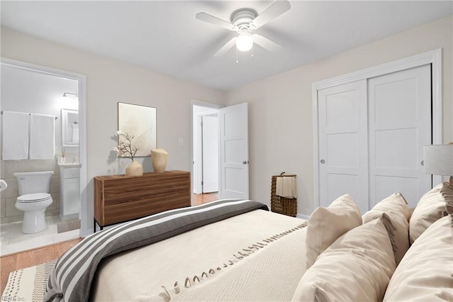 bedroom with a closet, connected bathroom, hardwood / wood-style floors, and ceiling fan