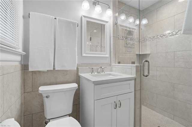 bathroom with toilet, tile walls, an enclosed shower, and vanity