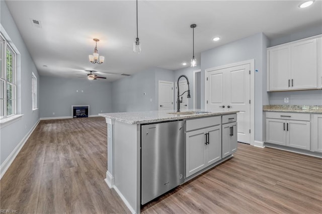 kitchen with sink, white cabinets, ceiling fan, an island with sink, and hanging light fixtures