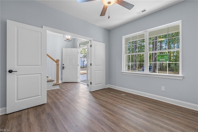 spare room featuring a healthy amount of sunlight, dark wood-type flooring, and ceiling fan with notable chandelier