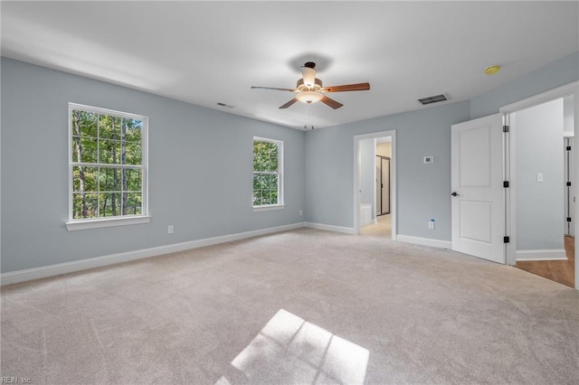 carpeted empty room with ceiling fan and a wealth of natural light