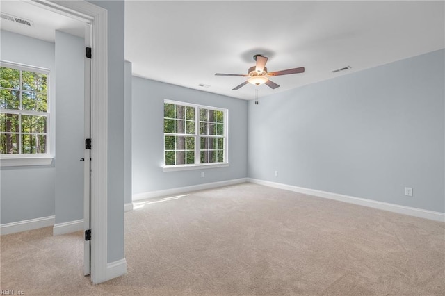 carpeted empty room with ceiling fan and plenty of natural light