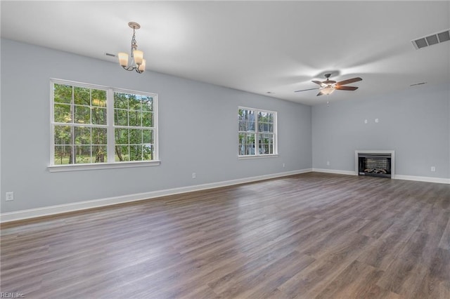 unfurnished living room featuring a healthy amount of sunlight, hardwood / wood-style floors, and ceiling fan with notable chandelier